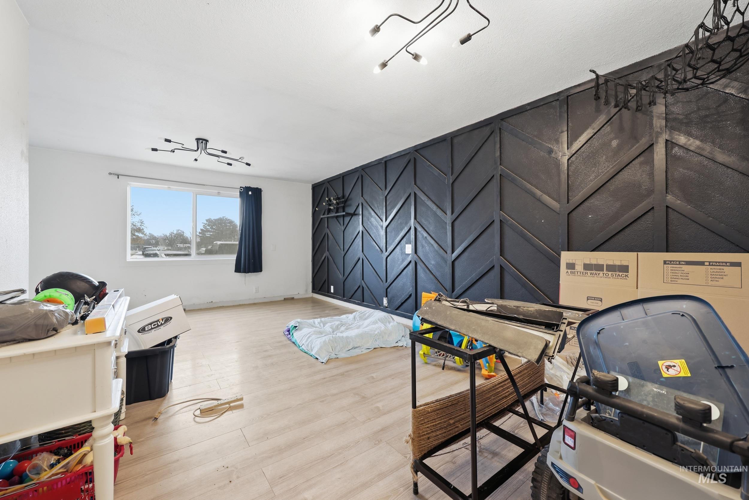 Rec room with an accent wall and light wood-style floors