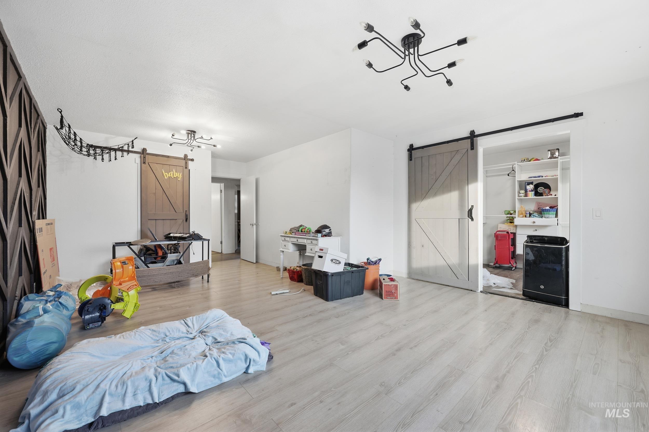Bedroom with a barn door and light wood finished floors