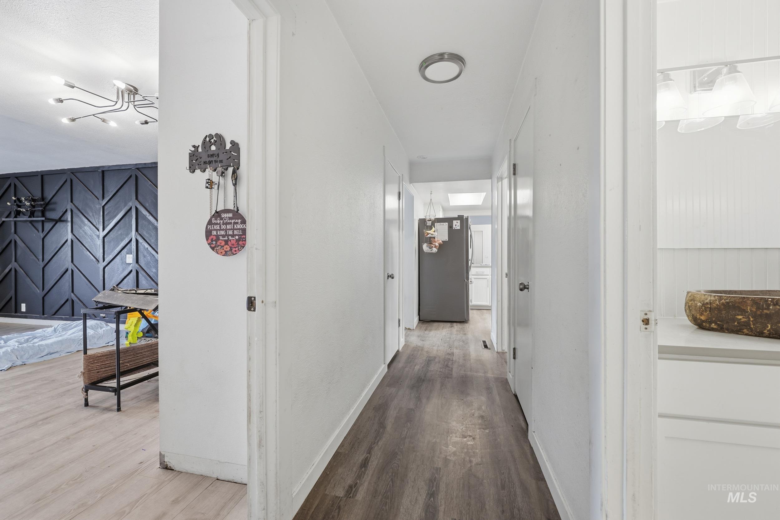 Hall with dark wood-style flooring and baseboards