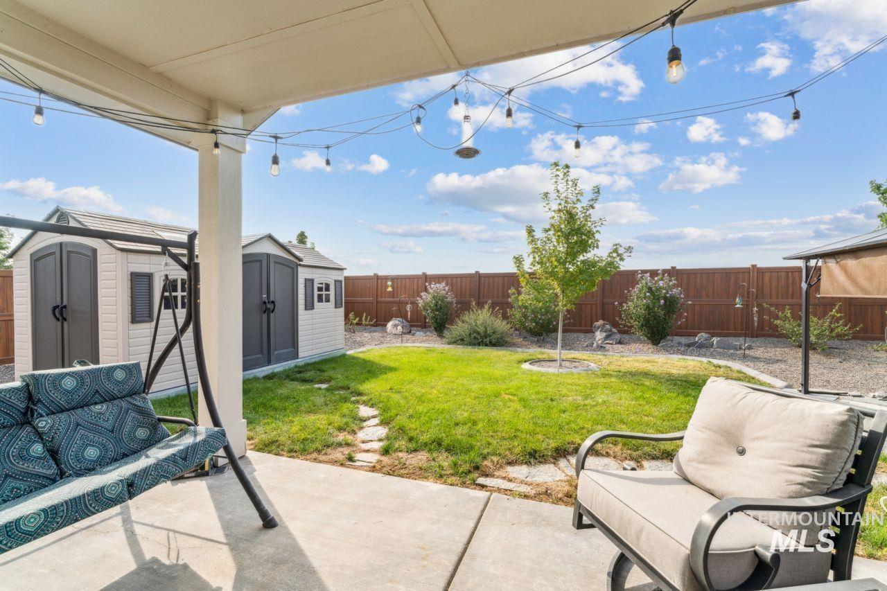 Fenced backyard with a storage unit and a patio area