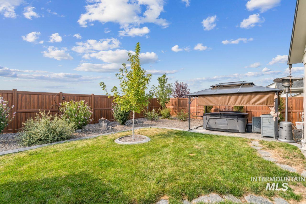 Fenced backyard with a hot tub, a gazebo, and a patio area