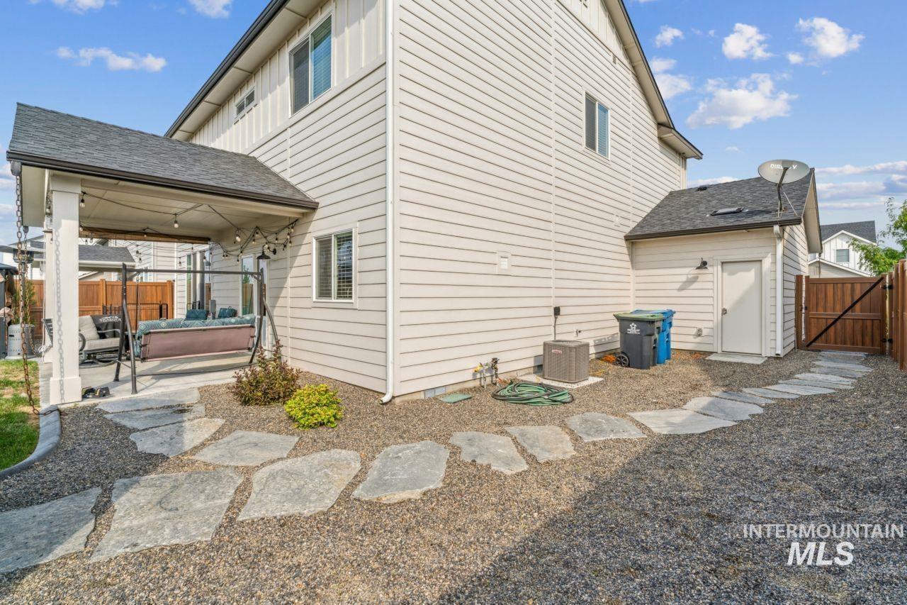 Rear view of property featuring a gate, a patio, and roof with shingles