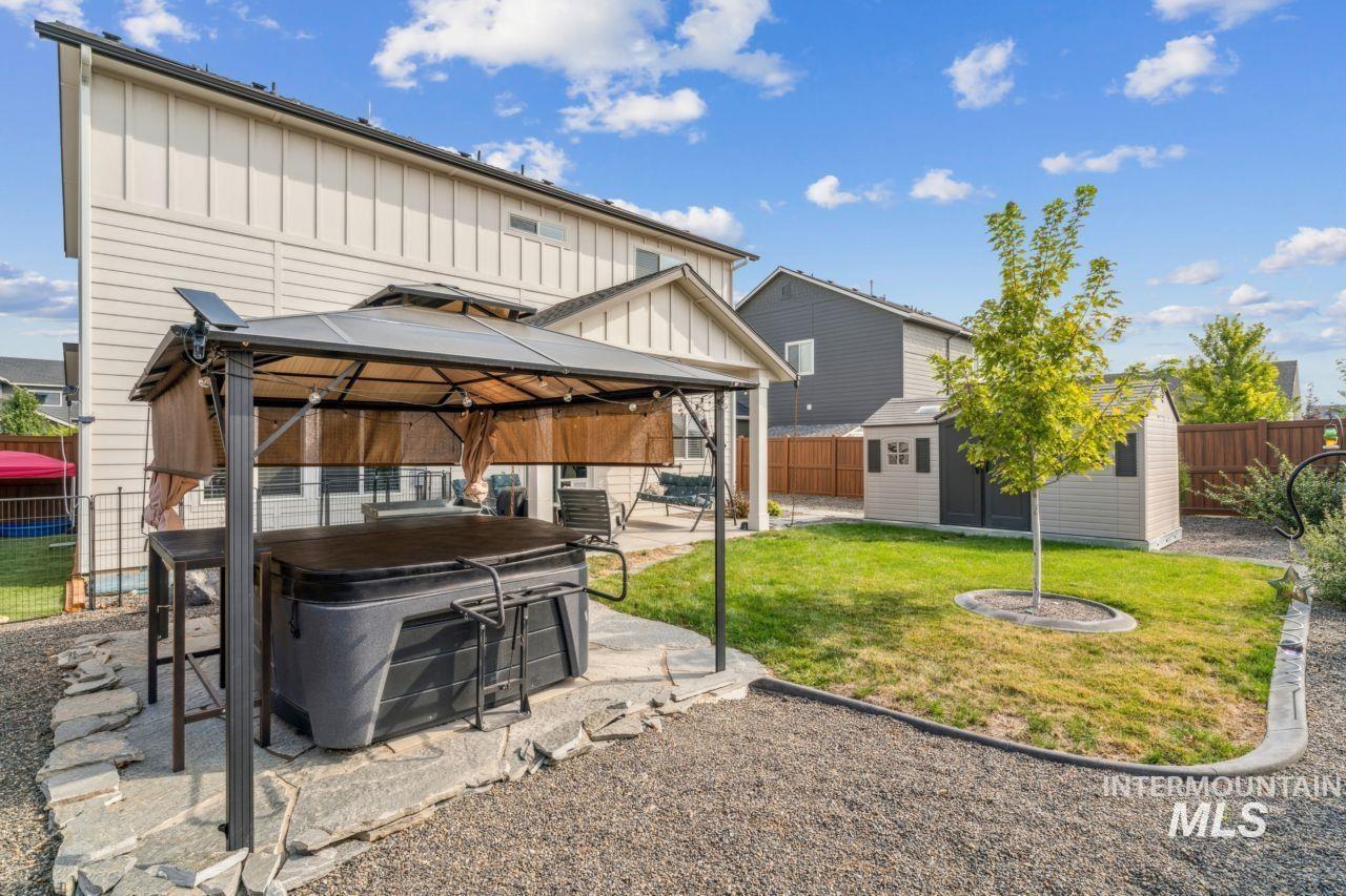 Back of house with board and batten siding, a gazebo, a fenced backyard, and a patio