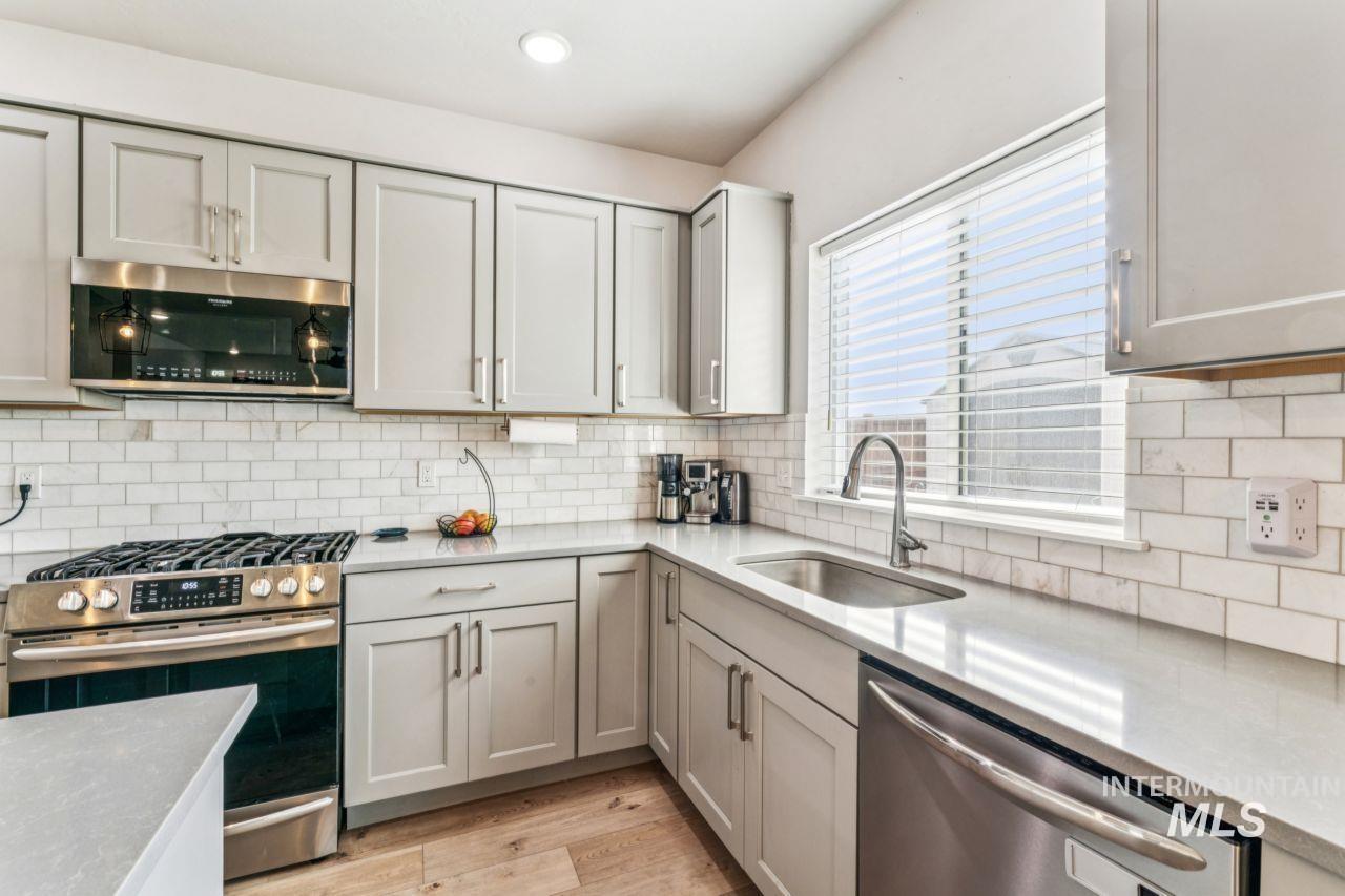 Kitchen featuring stainless steel appliances, light stone counters, light wood finished floors, gray cabinetry, and recessed lighting