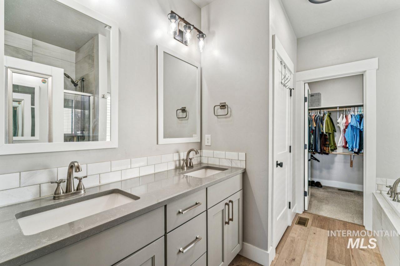 Bathroom with a stall shower, double vanity, a spacious closet, and light wood-style flooring
