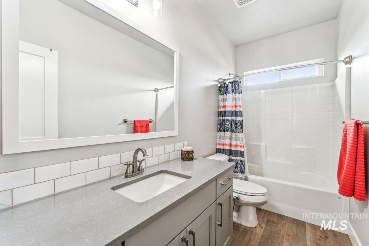 Bathroom with vanity, shower / tub combo with curtain, and dark wood-style floors