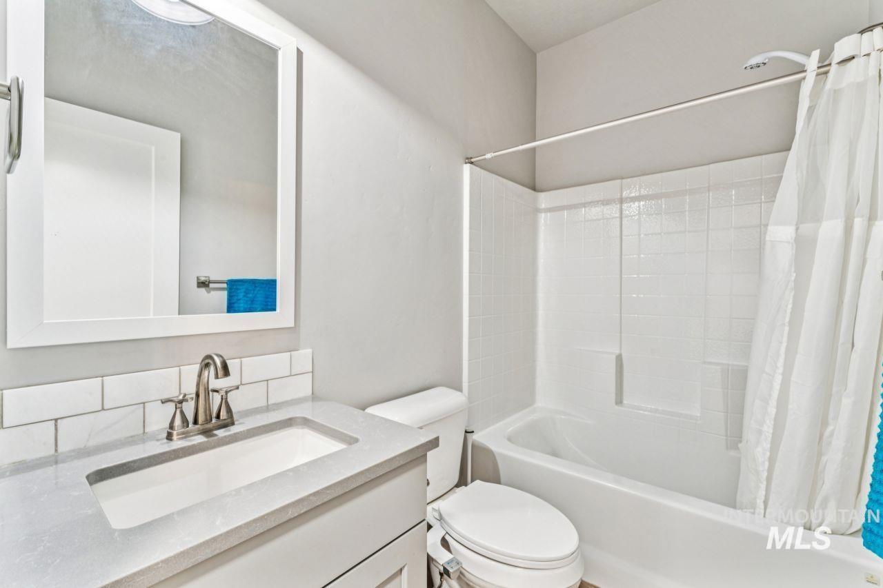 Full bath with shower / bathtub combination with curtain, vanity, and backsplash