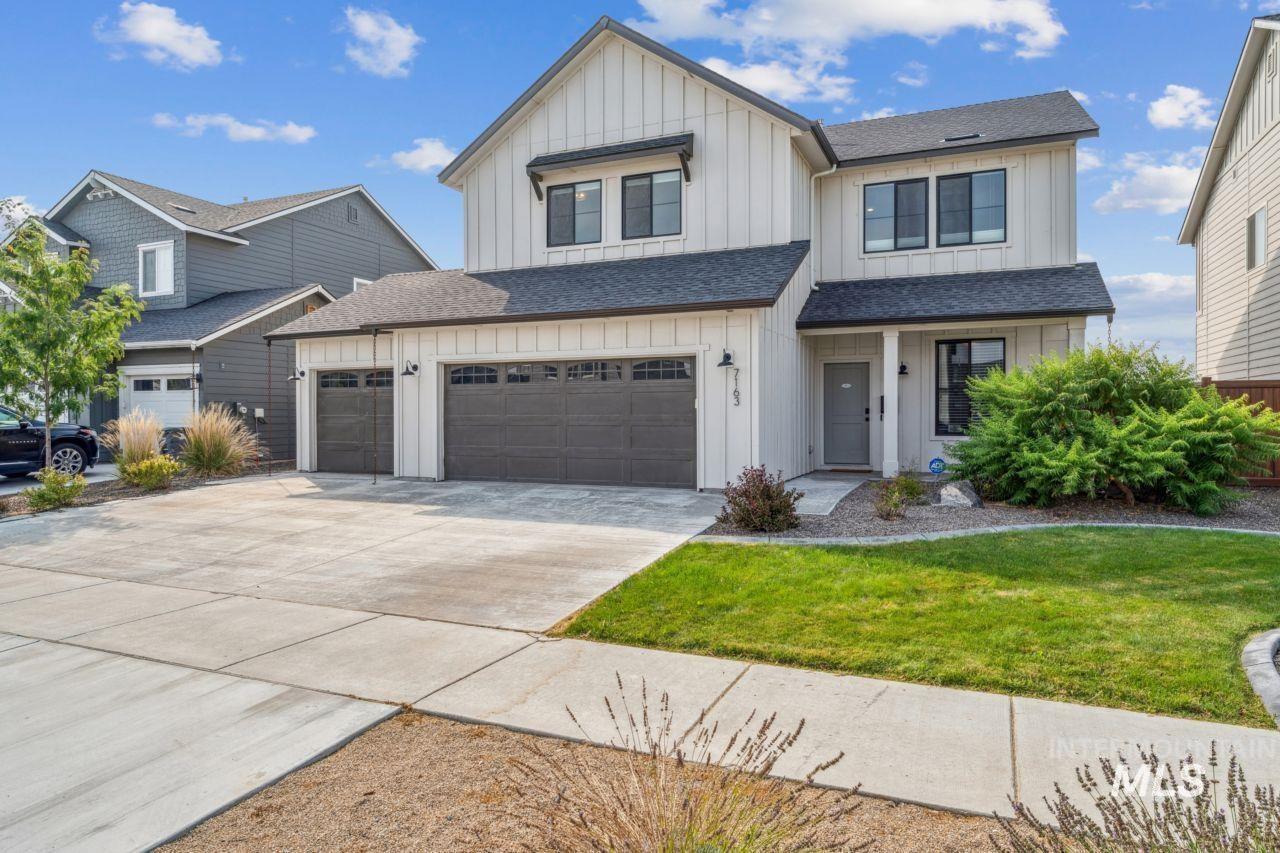 Modern farmhouse featuring board and batten siding, a front lawn, a shingled roof, driveway, and covered porch