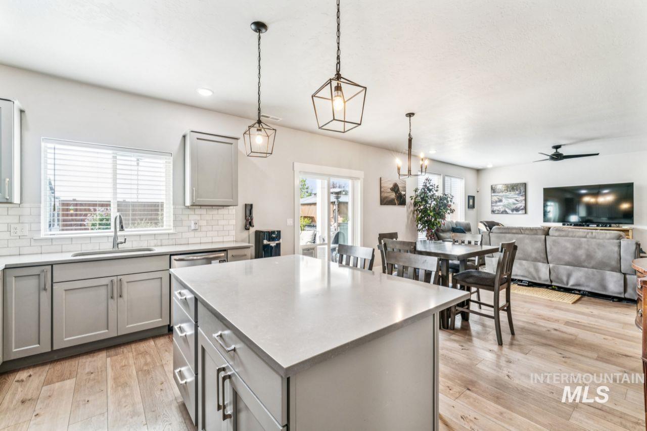 Kitchen featuring gray cabinets, a center island, backsplash, hanging light fixtures, and light wood-style floors