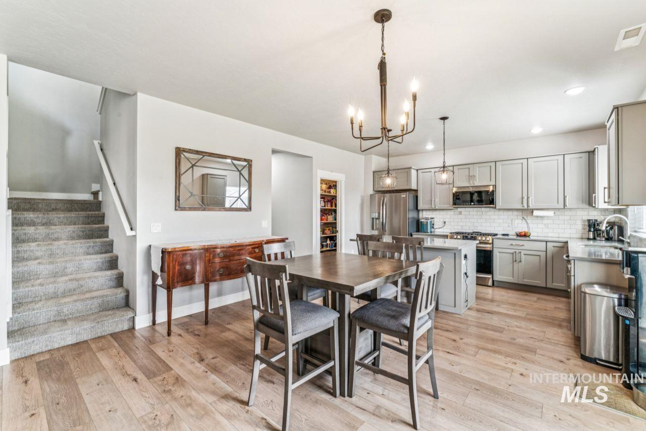 Dining area with light wood-style floors, a chandelier, stairs, and recessed lighting