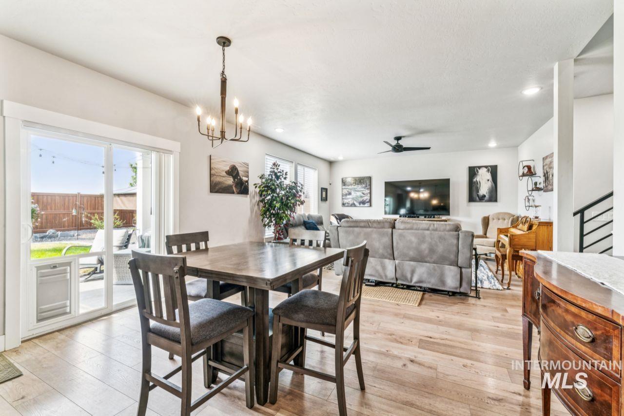 Dining room with light wood-style floors, ceiling fan, a chandelier, and stairway