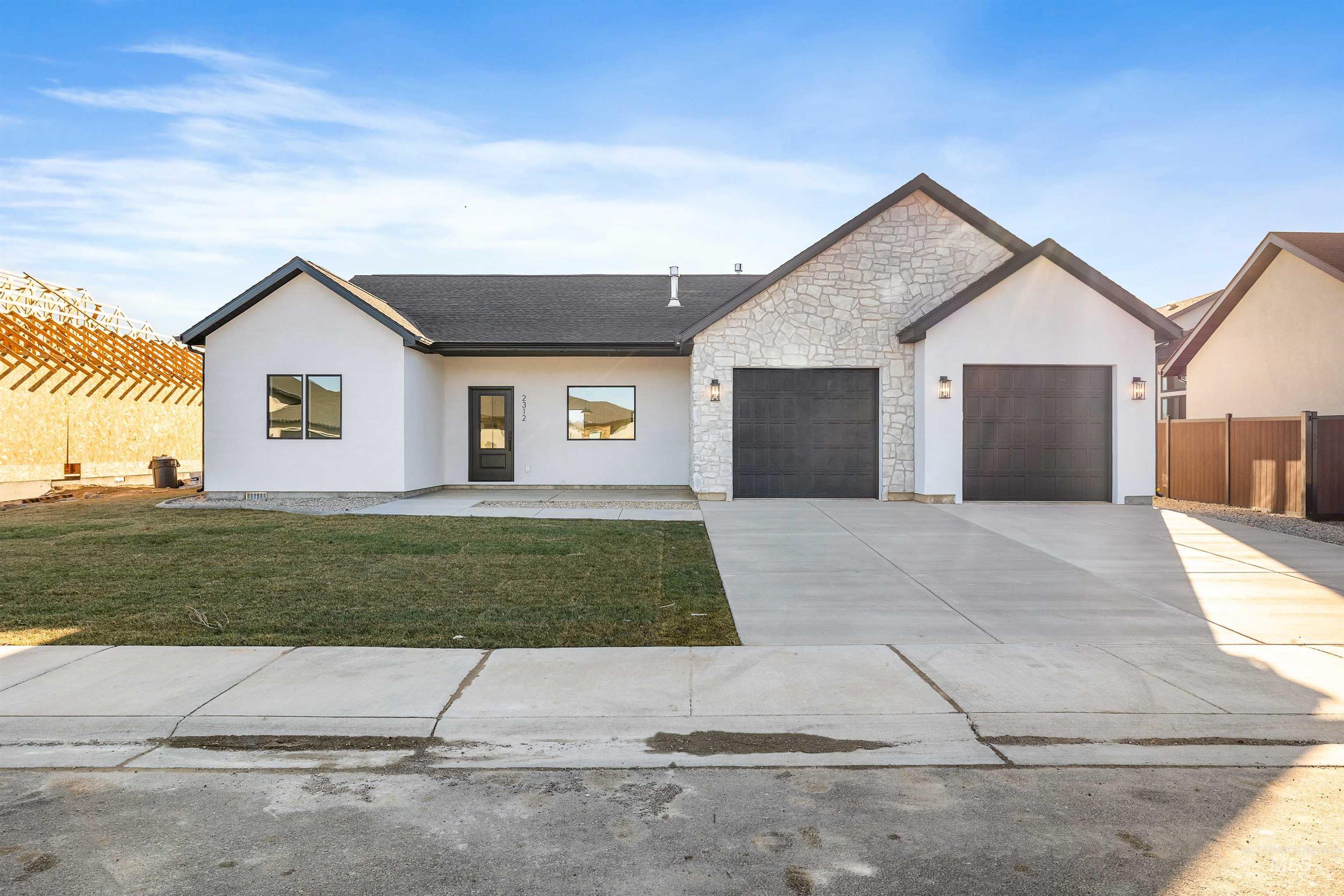 View of front facade with stone siding, concrete driveway, stucco siding, and an attached garage