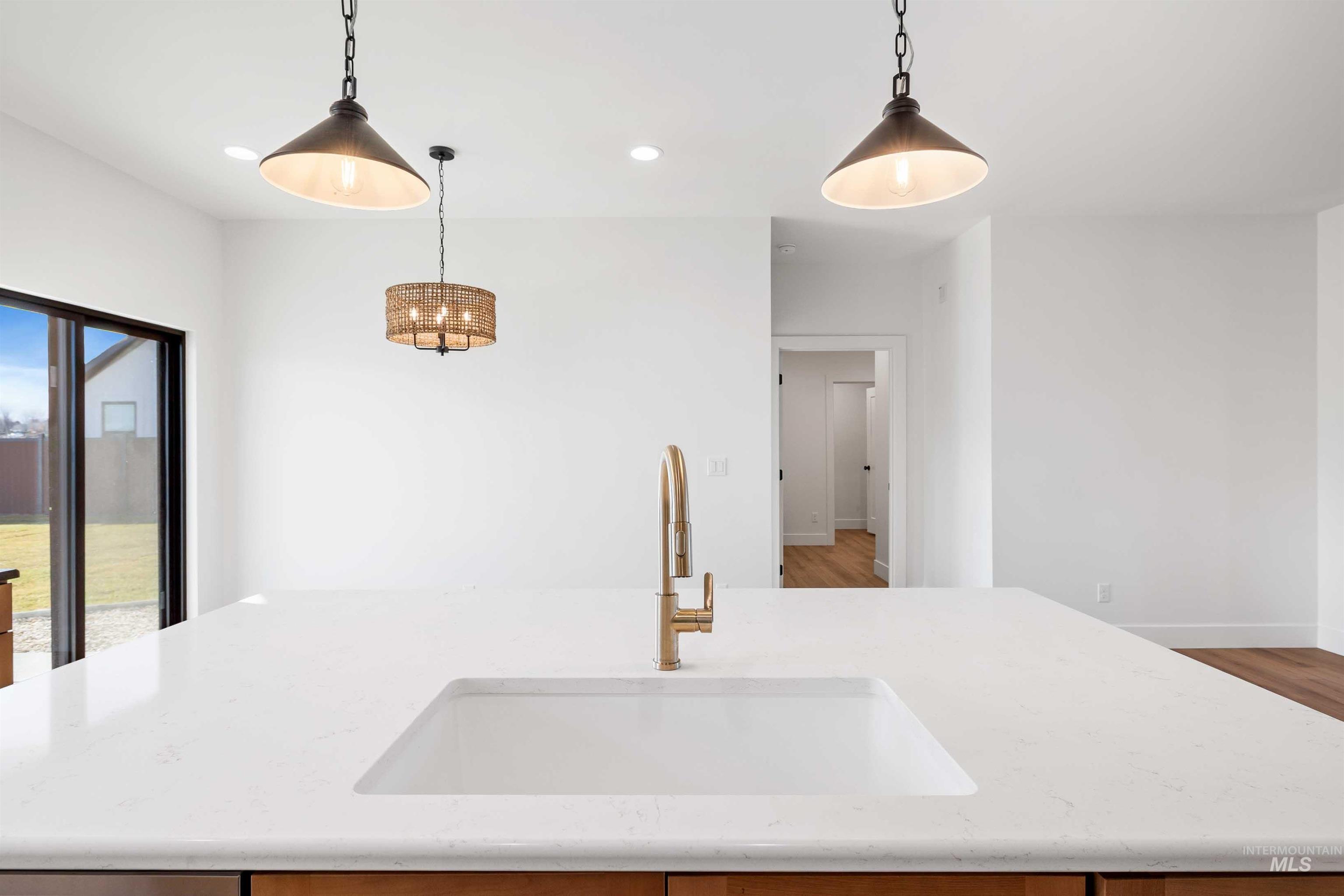 Kitchen featuring a kitchen island with sink, light stone counters, recessed lighting, and decorative light fixtures