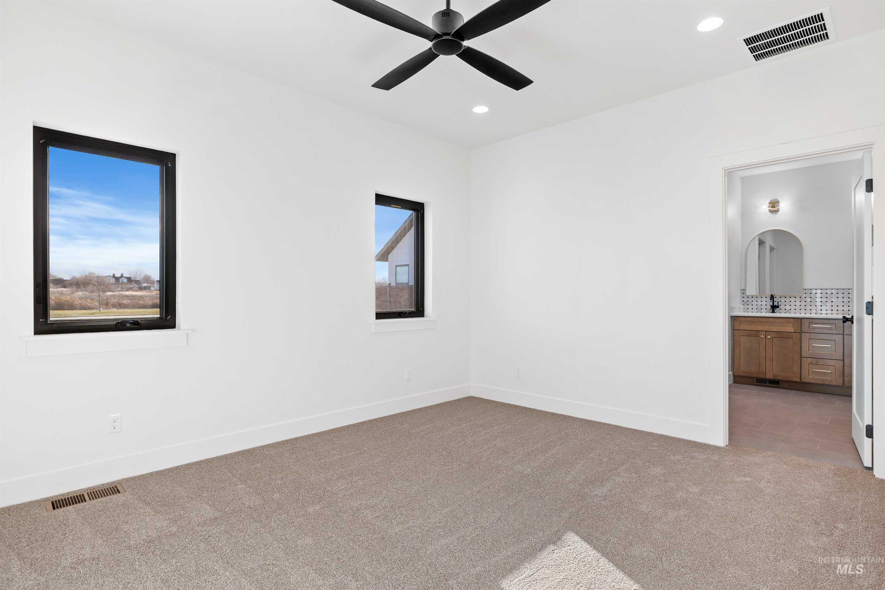 Unfurnished bedroom featuring light colored carpet, connected bathroom, recessed lighting, and a ceiling fan