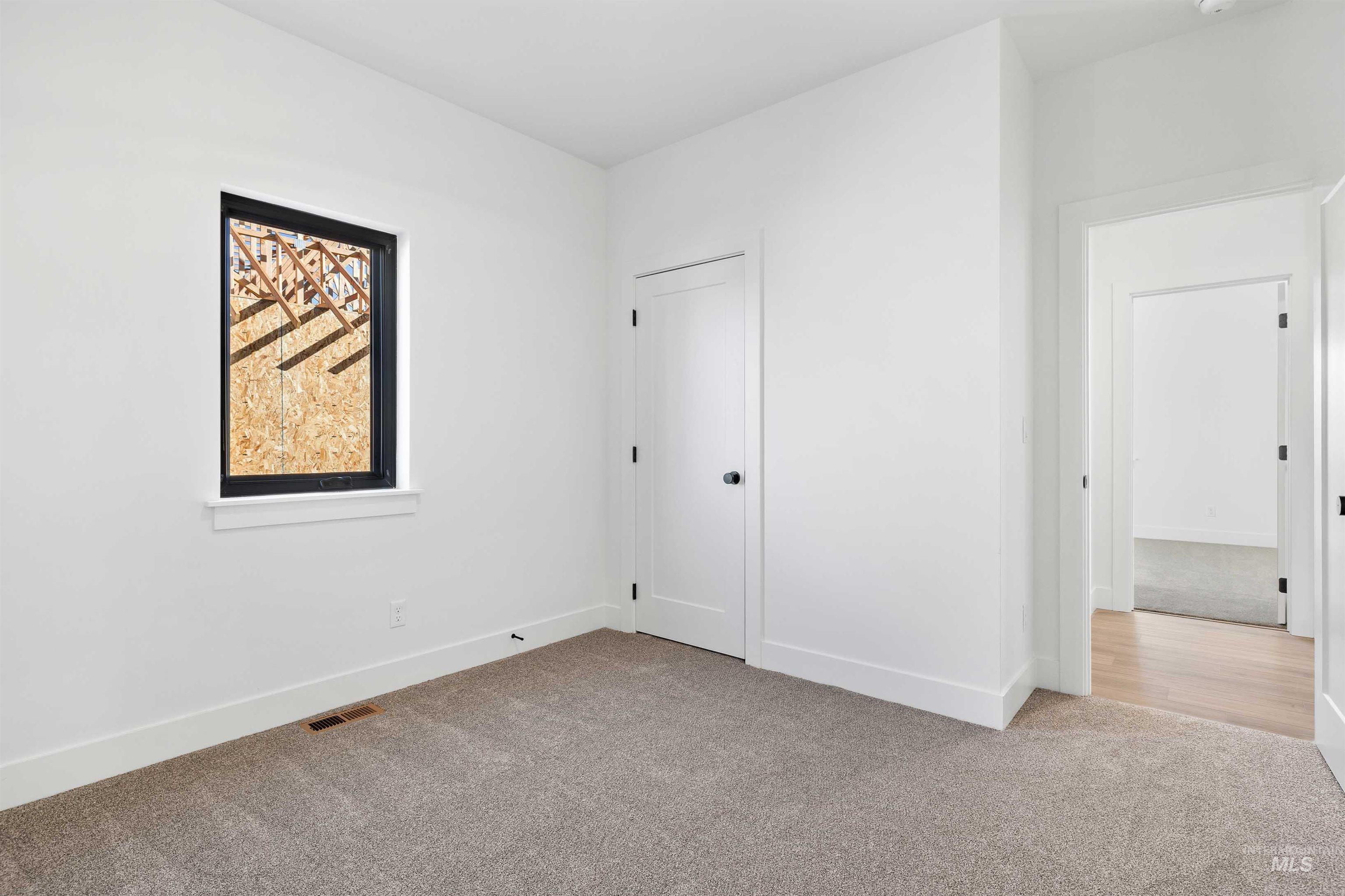 Unfurnished bedroom with light carpet and baseboards