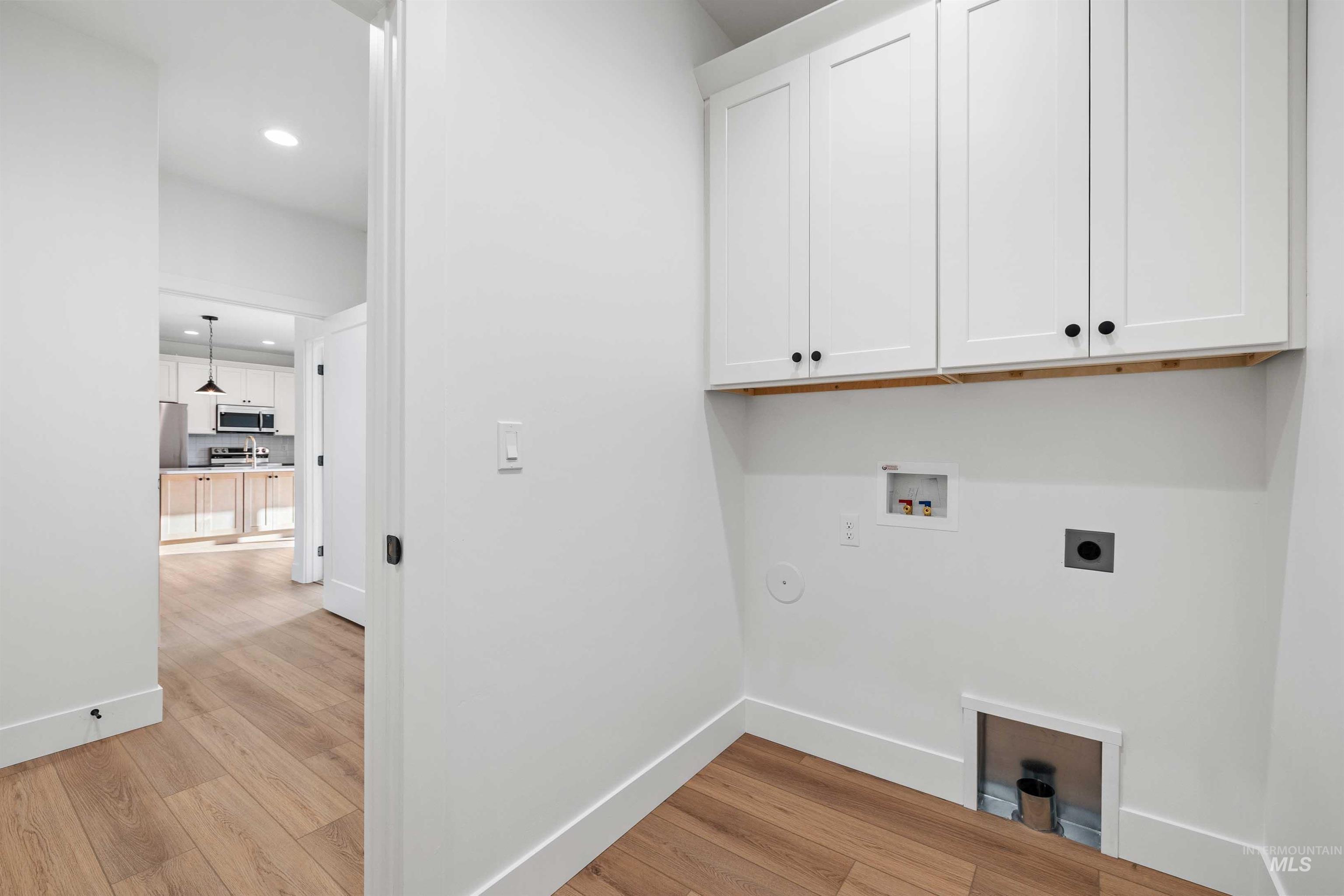 Laundry area with hookup for a washing machine, recessed lighting, cabinet space, electric dryer hookup, and light wood-type flooring