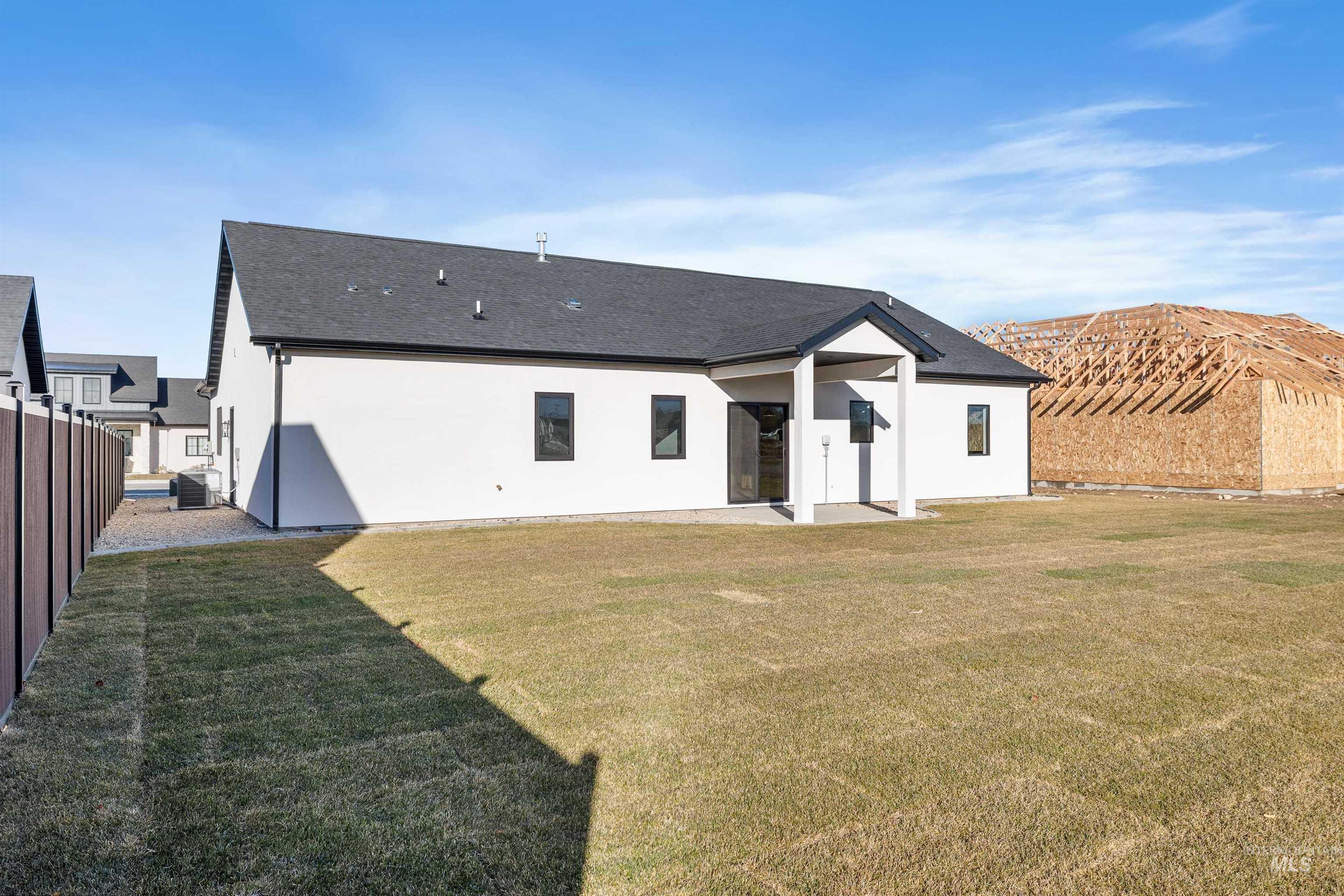 Rear view of house with a patio area, stucco siding, and a shingled roof