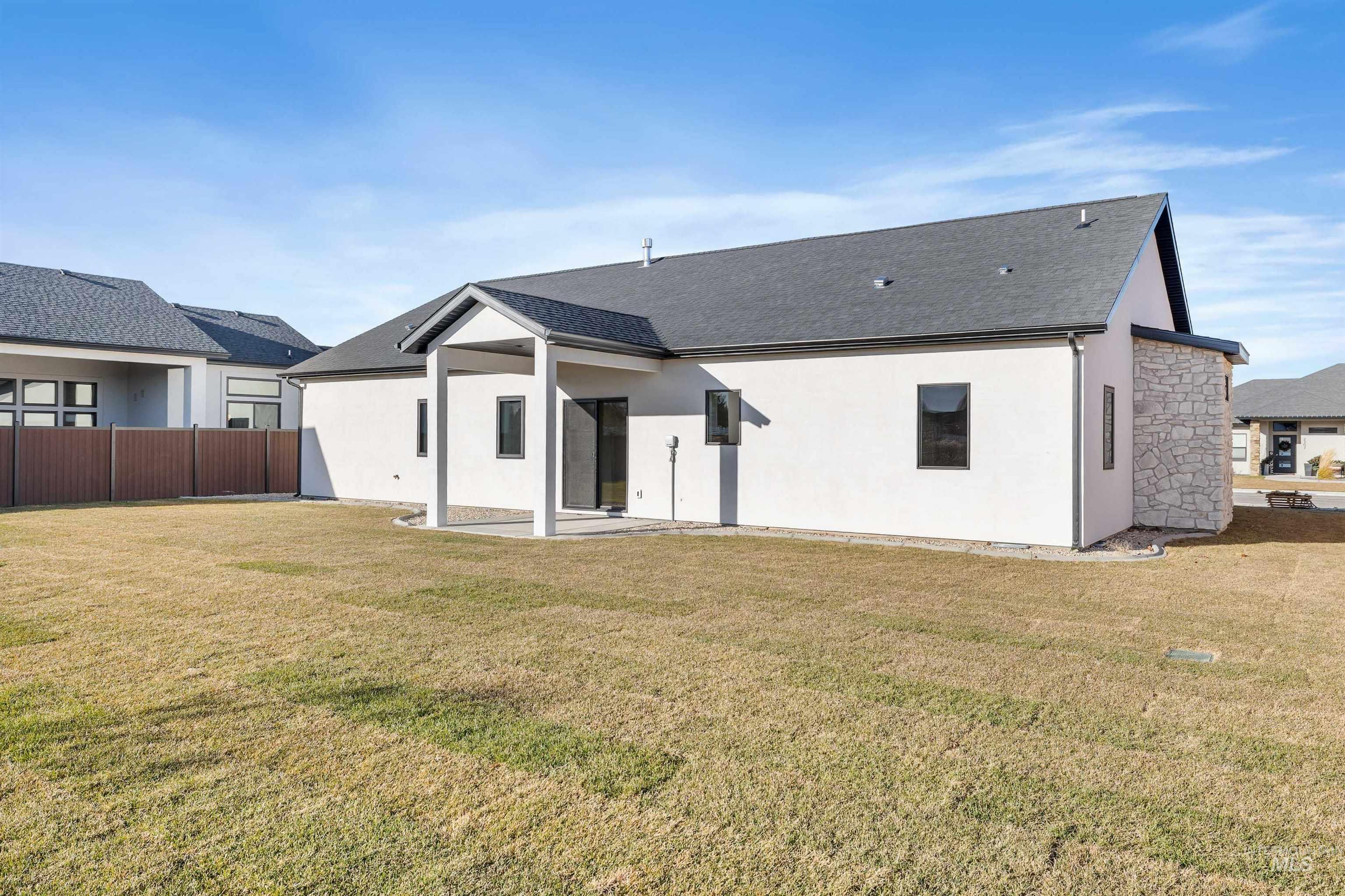 Rear view of house with a patio, stucco siding, and a shingled roof