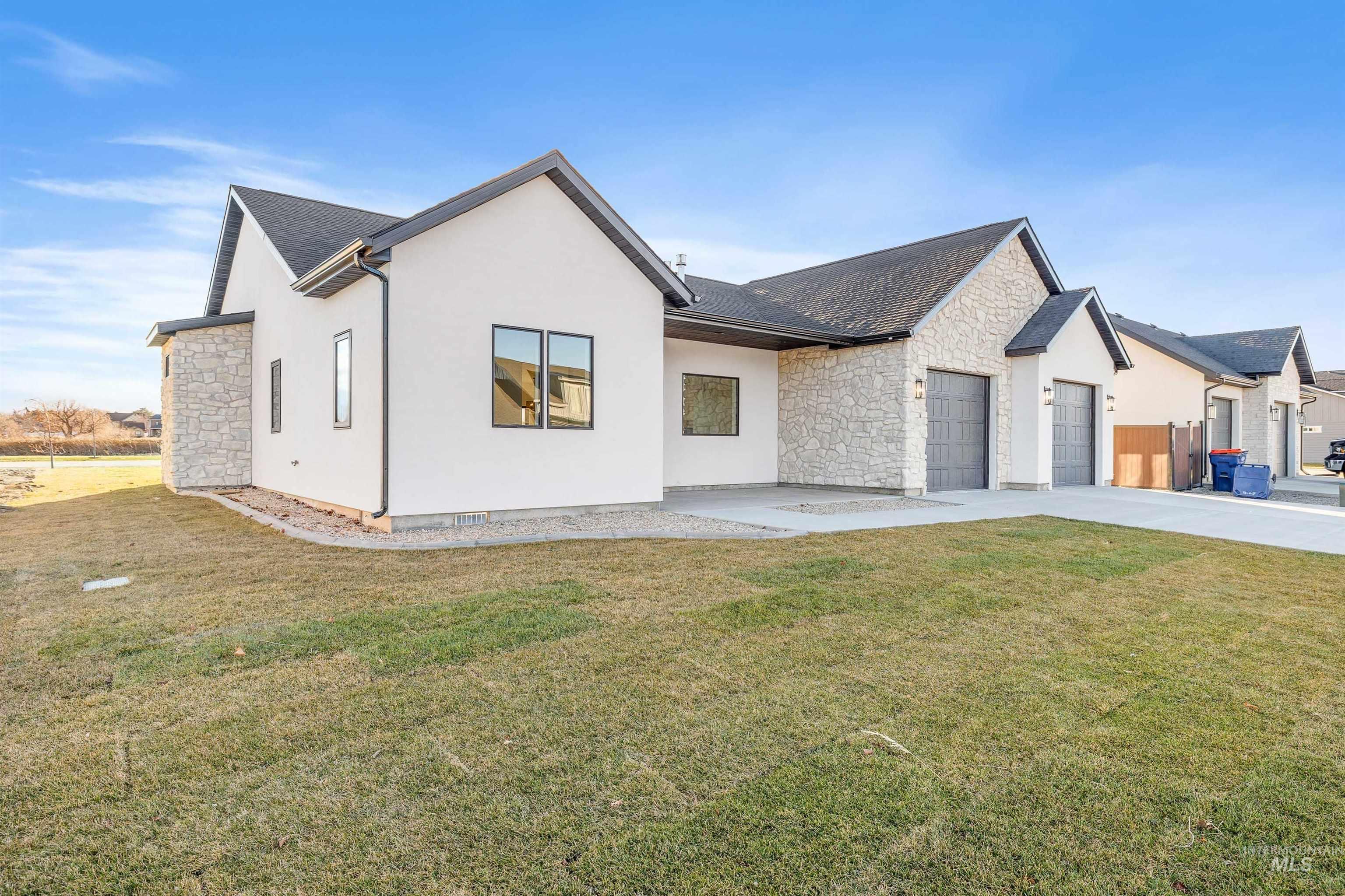 View of front of home featuring stone siding, a front yard, stucco siding, and a garage