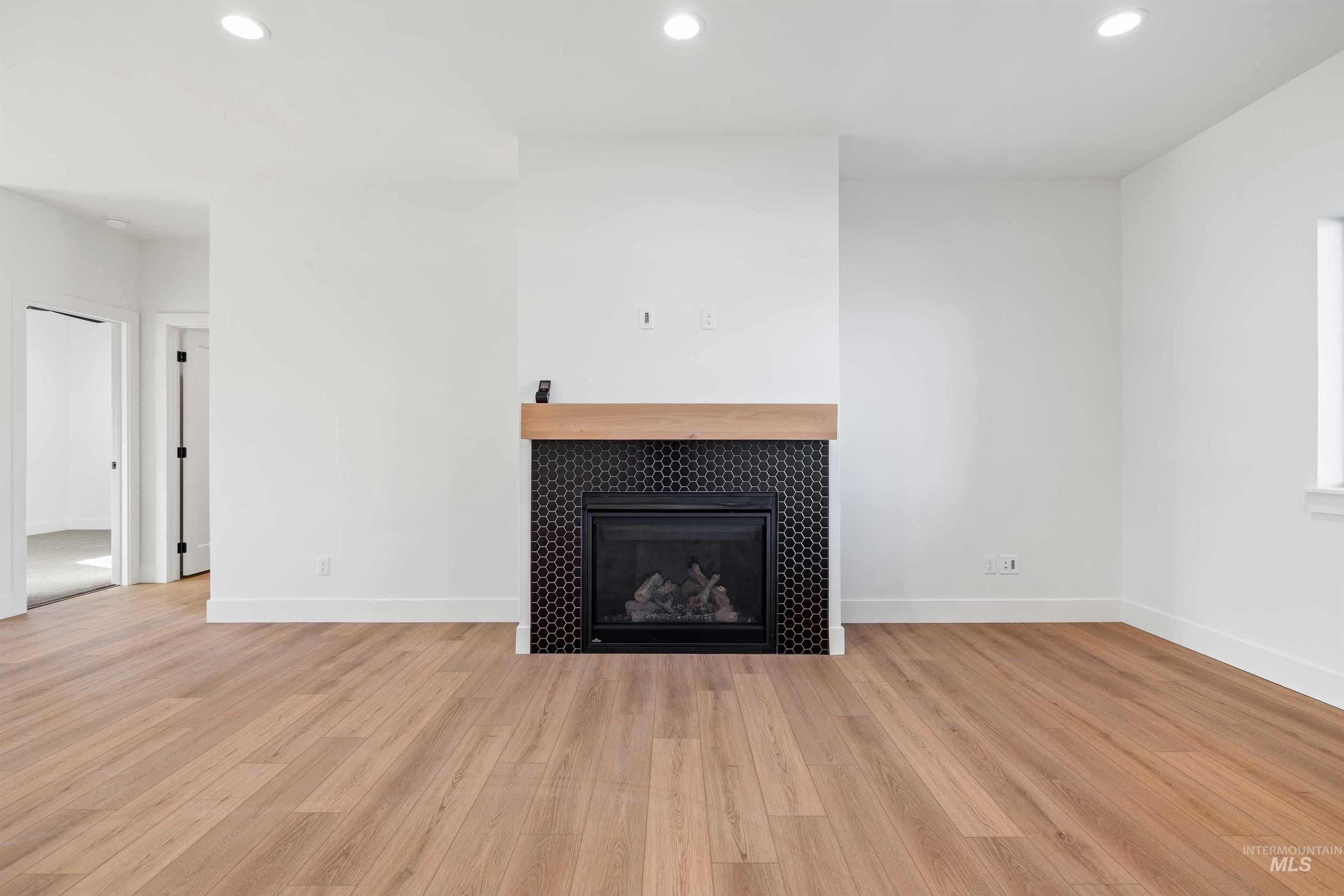 Unfurnished living room with recessed lighting, a tiled fireplace, and light wood-type flooring