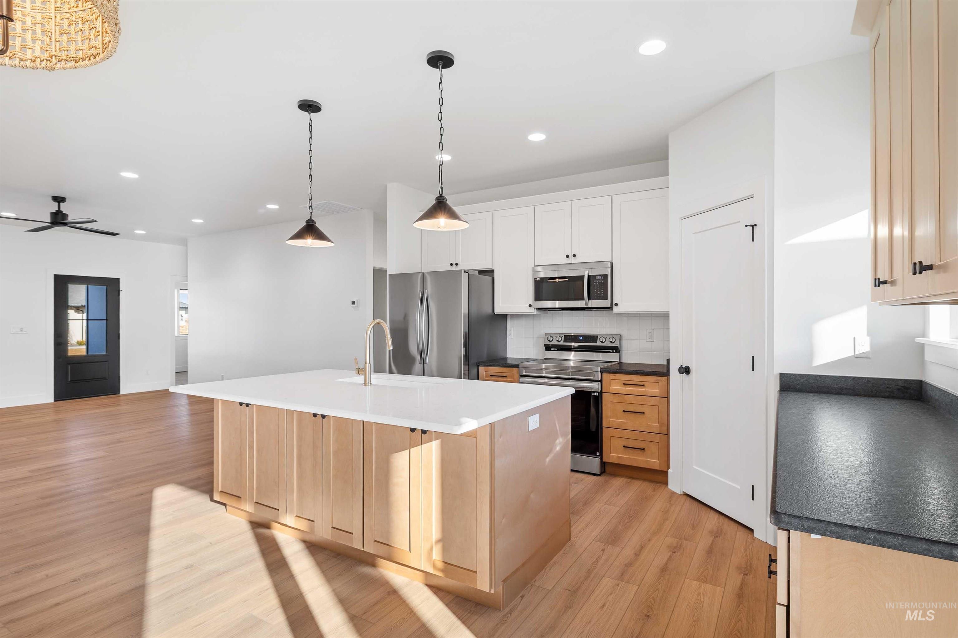 Kitchen with stainless steel appliances, light brown cabinets, recessed lighting, an island with sink, and light wood-type flooring