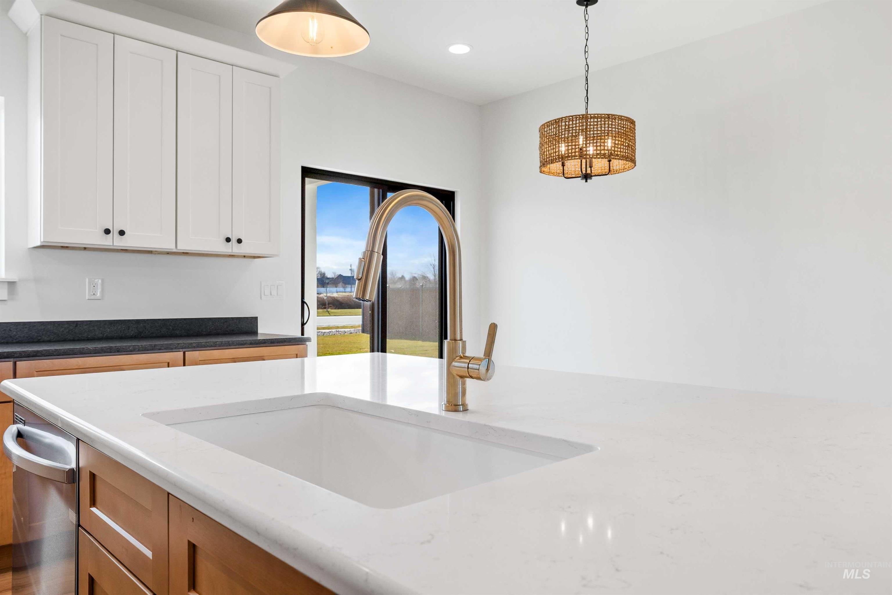 Kitchen featuring dark stone counters, pendant lighting, recessed lighting, dishwasher, and white cabinetry