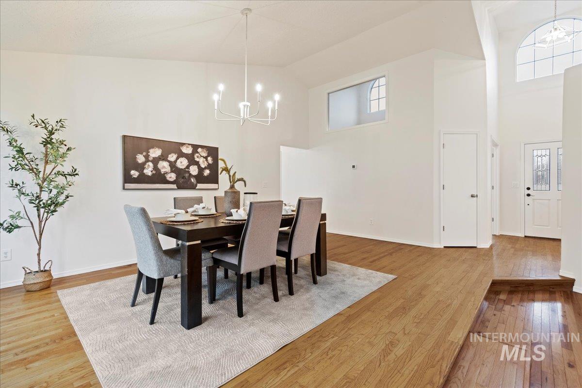Dining room with a chandelier, light wood-style flooring, and high vaulted ceiling