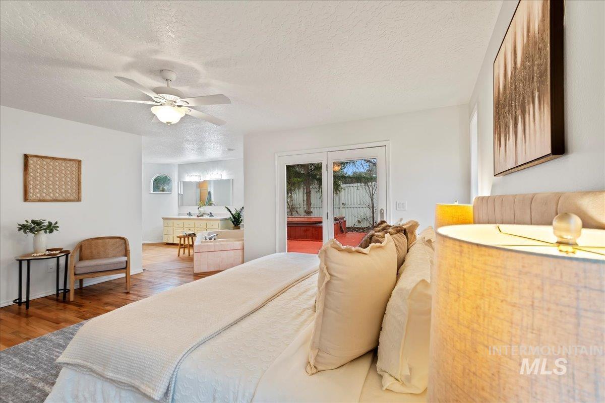 Bedroom with a textured ceiling, access to outside, a ceiling fan, and wood finished floors