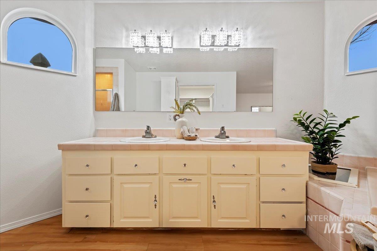 Bathroom with double vanity, light wood-style flooring, and a textured wall