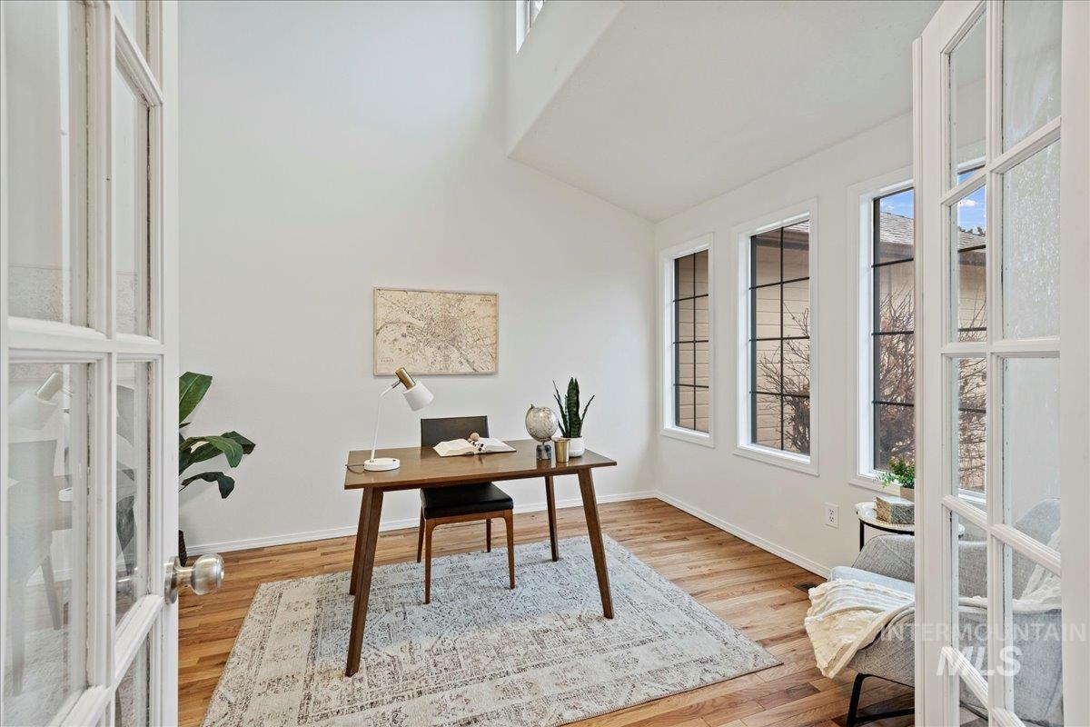 Office space with healthy amount of natural light, french doors, light wood-type flooring, and high vaulted ceiling