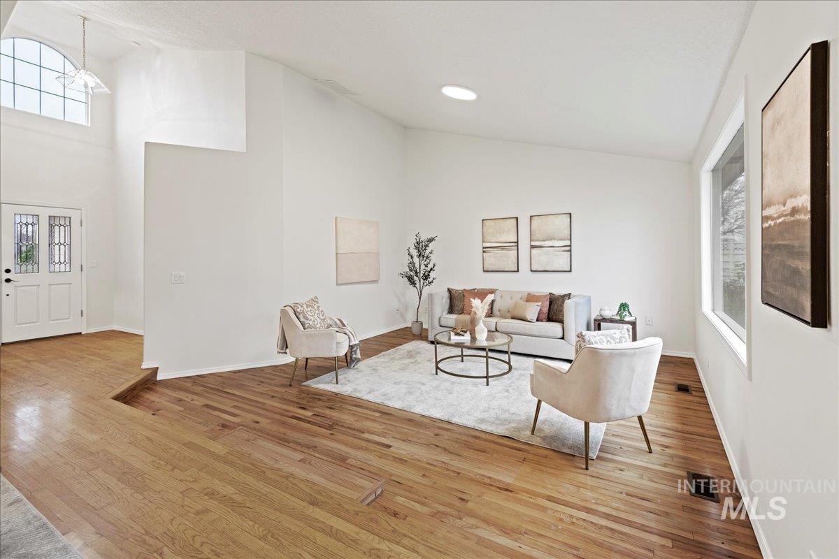 Living area with plenty of natural light, light wood-style flooring, and high vaulted ceiling