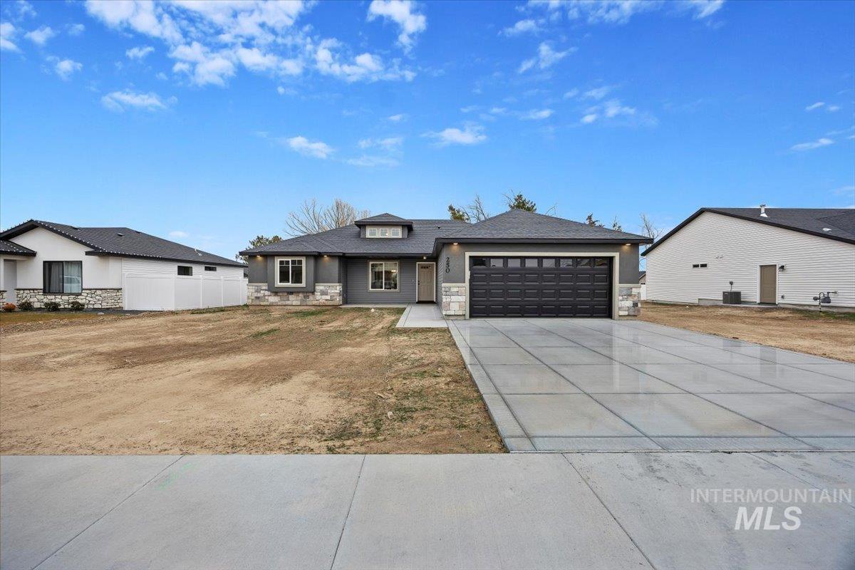 Prairie-style home with stone siding, an attached garage, and concrete driveway