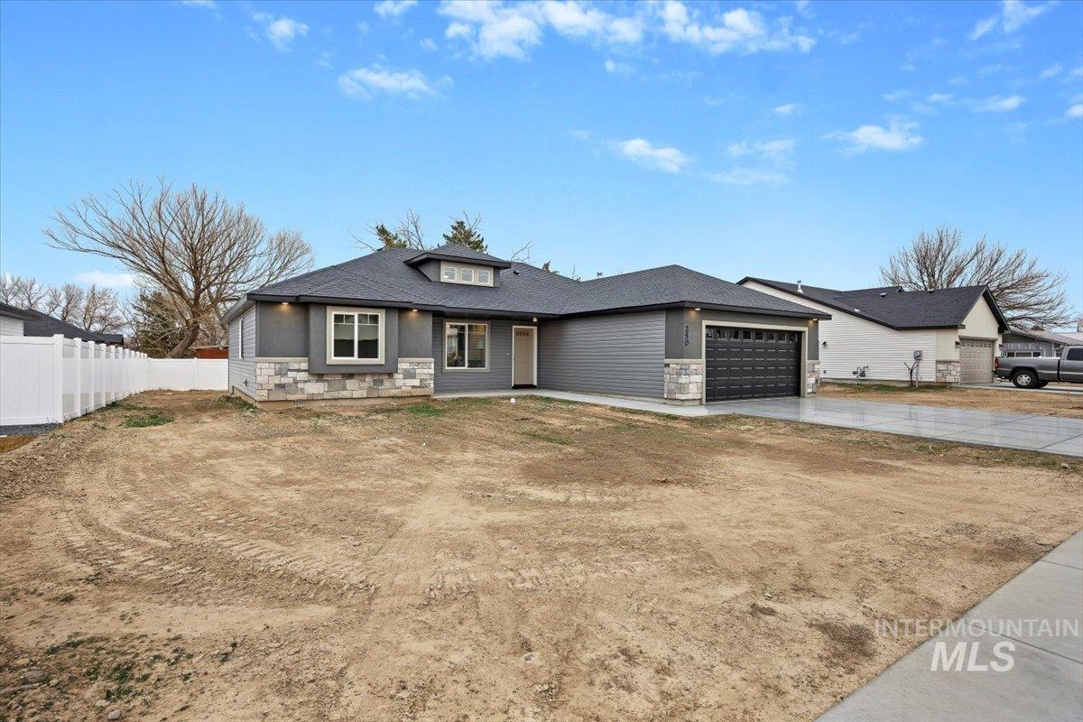 Bungalow featuring stone siding, driveway, and a garage