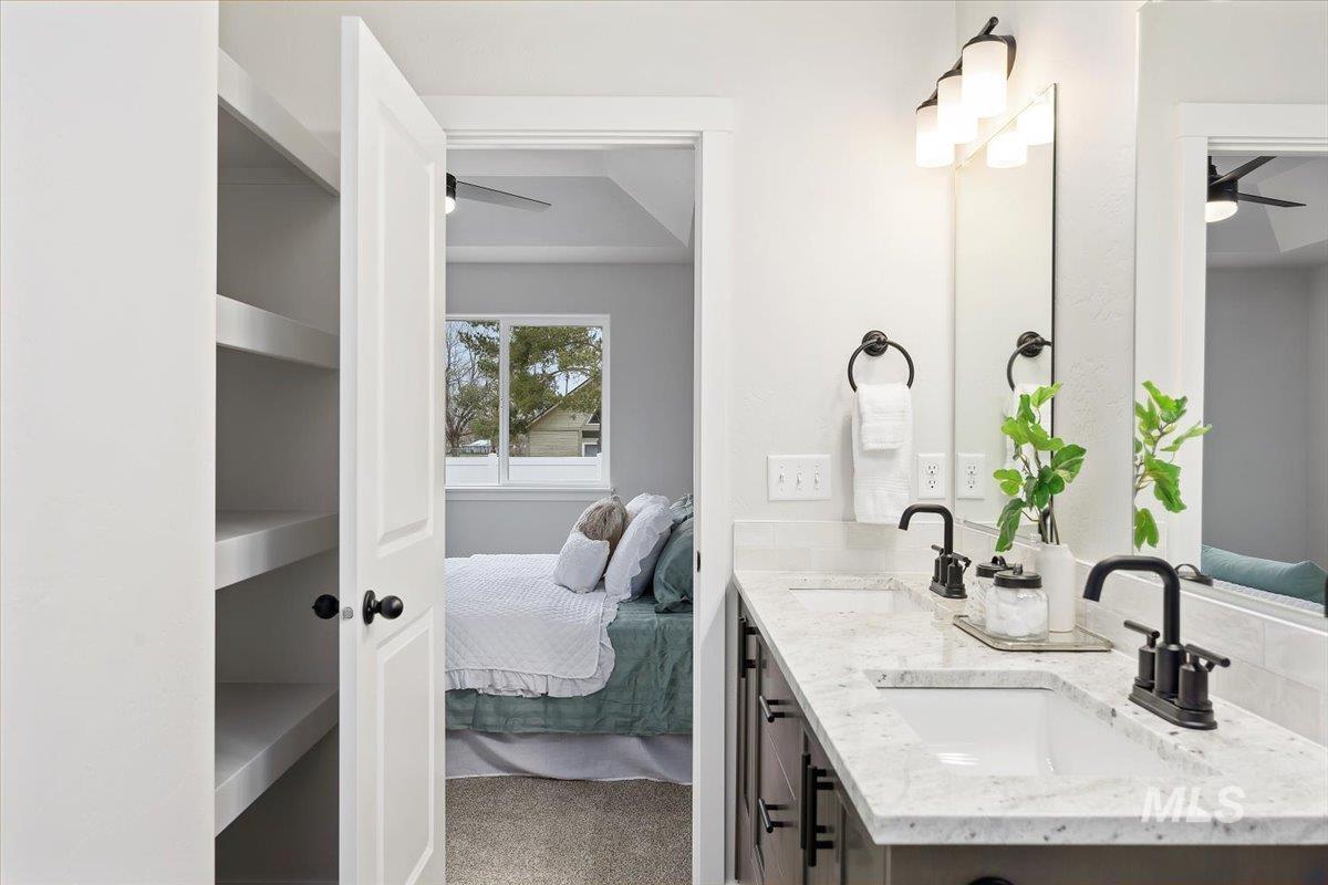 Full bath with ceiling fan, ensuite bathroom, light colored carpet, and double vanity