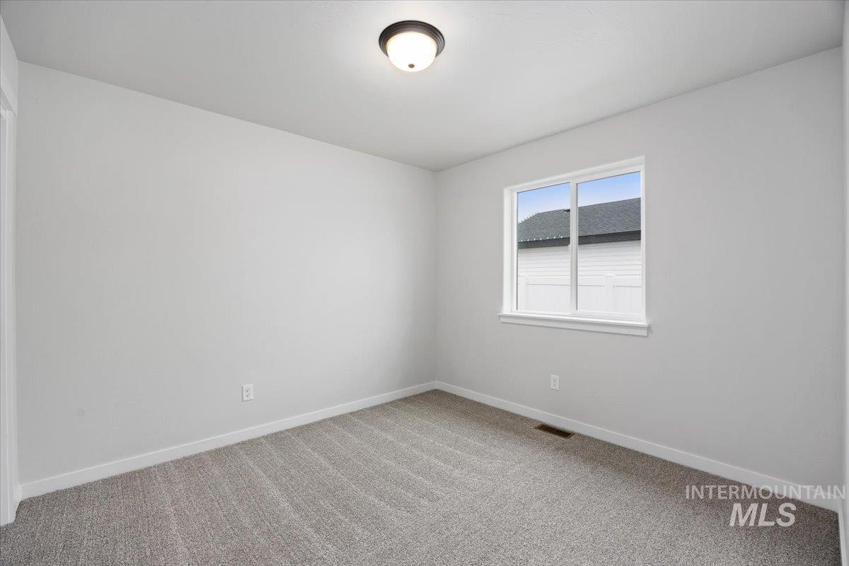 Spare room featuring light carpet and baseboards