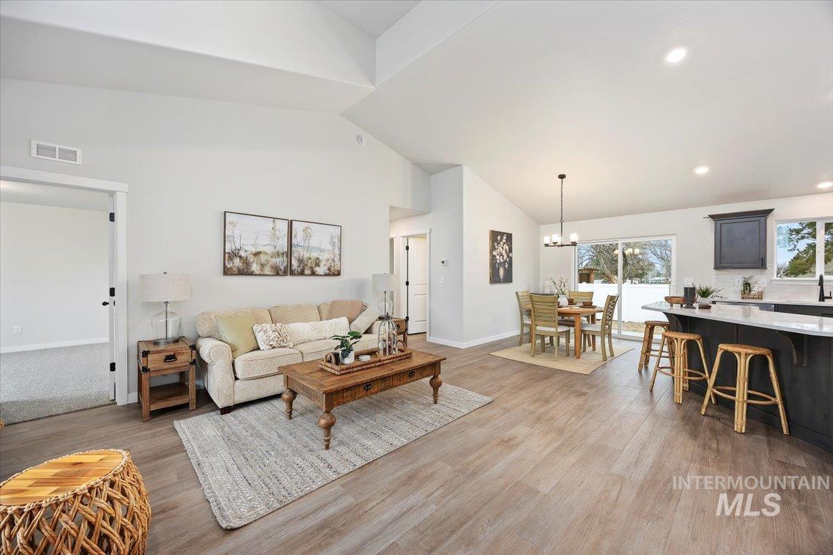 Living room featuring light wood-style floors, a chandelier, and high vaulted ceiling