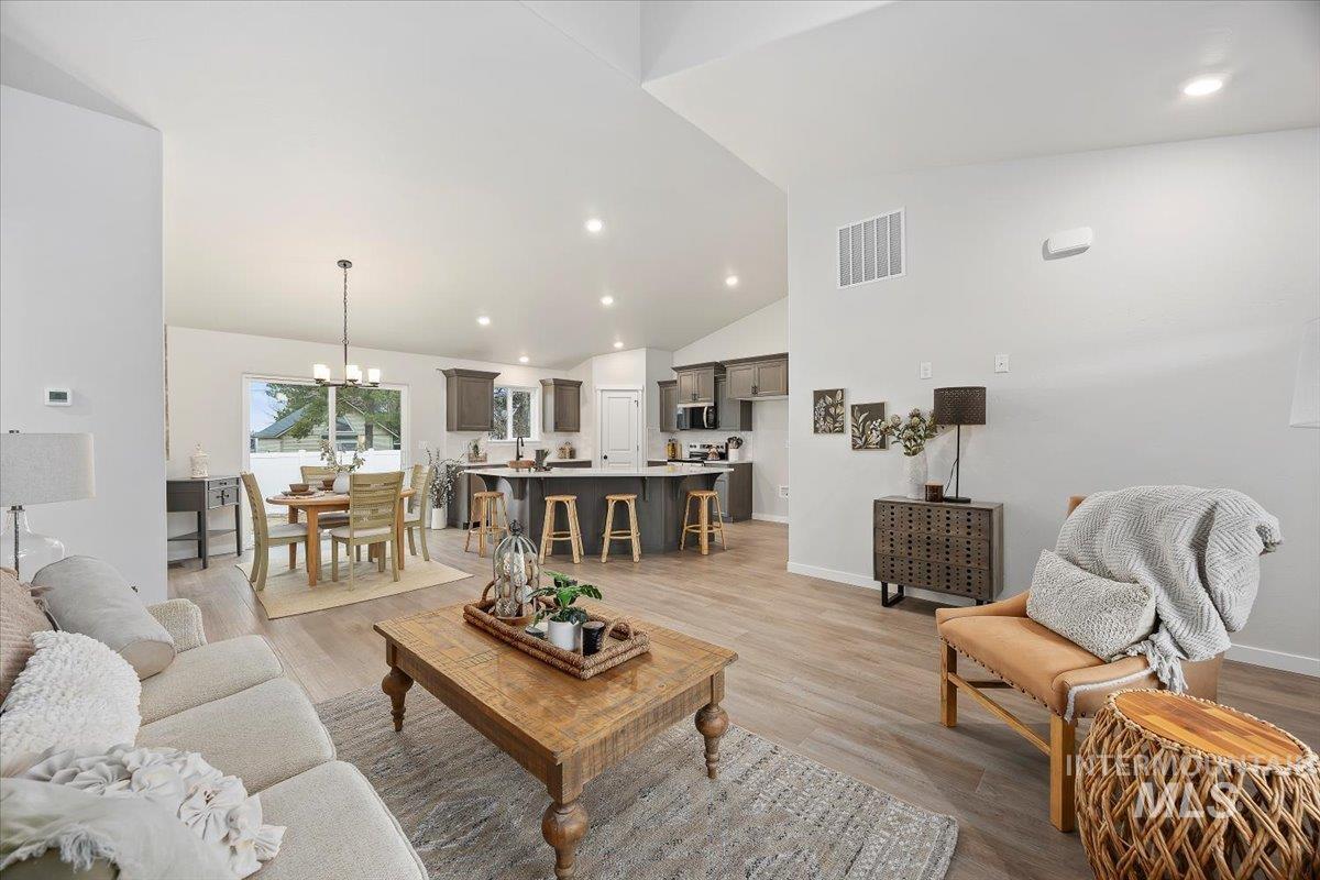Living room featuring a chandelier, recessed lighting, lofted ceiling, and light wood-type flooring