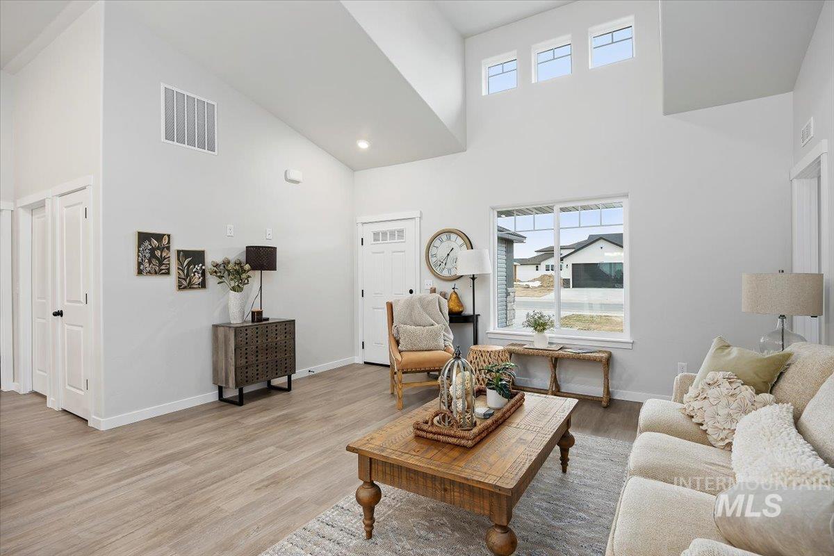 Living area with a high ceiling, wood finished floors, and recessed lighting