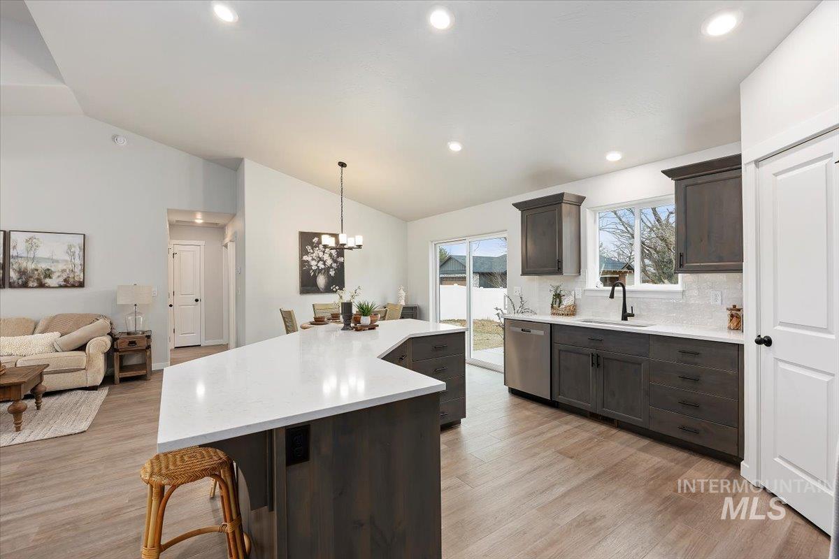 Kitchen featuring open floor plan, decorative light fixtures, a chandelier, vaulted ceiling, and a center island