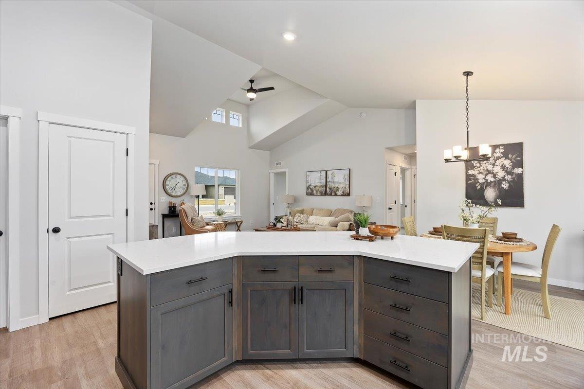 Kitchen with a center island, pendant lighting, open floor plan, a ceiling fan, and light wood finished floors