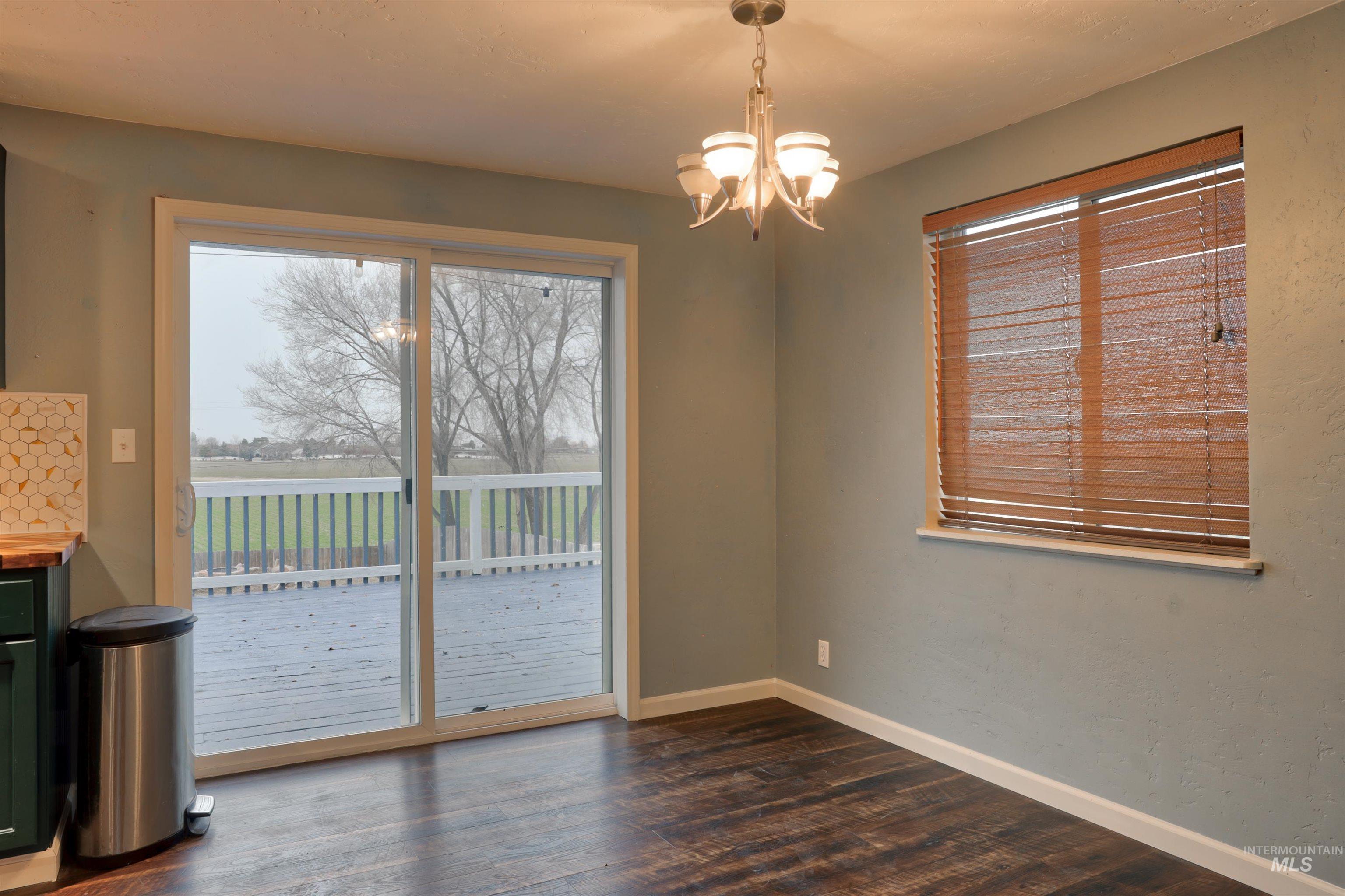 Unfurnished dining area featuring a chandelier and dark wood-type flooring