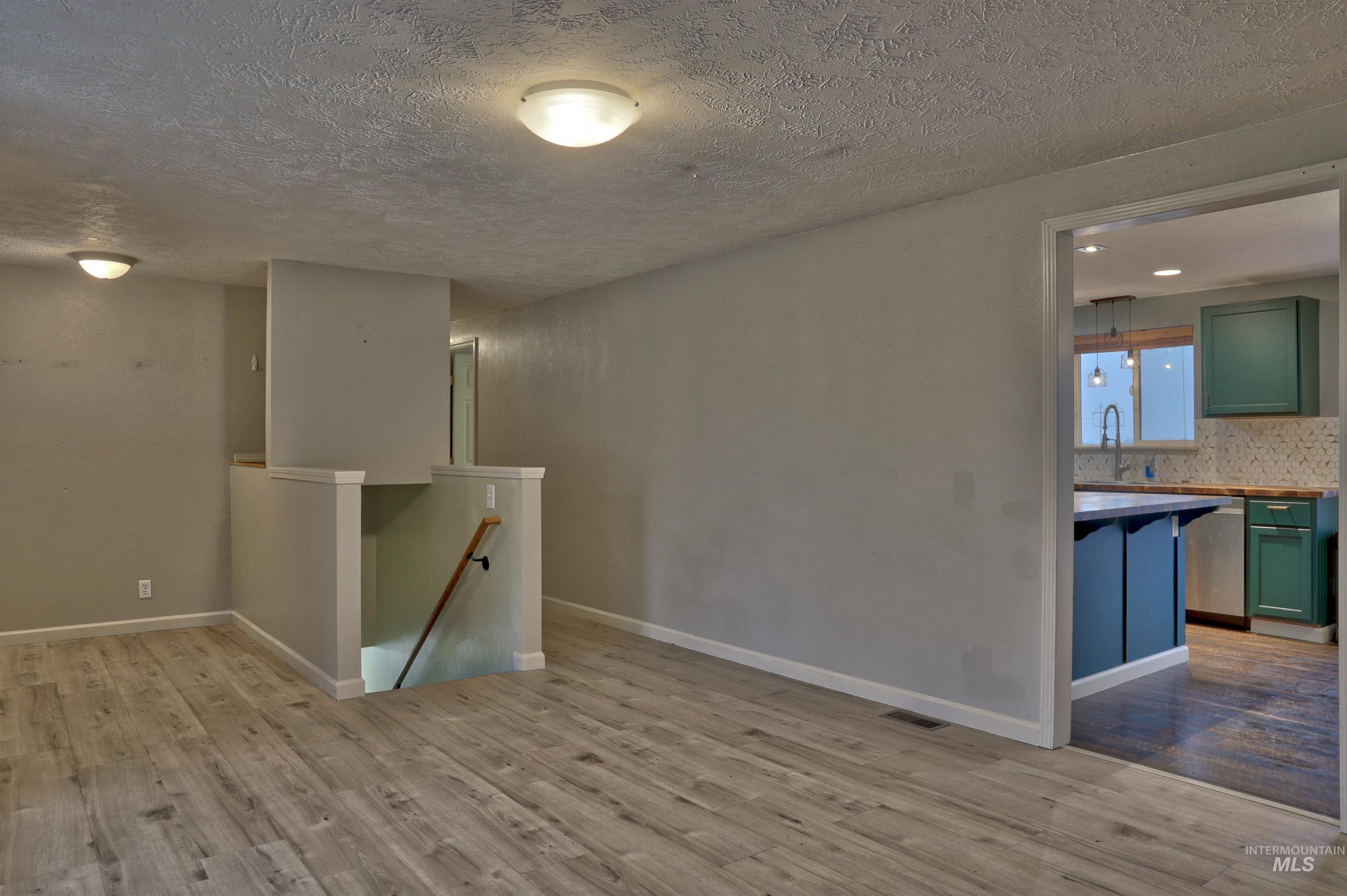 Empty room with a textured ceiling and light wood-type flooring