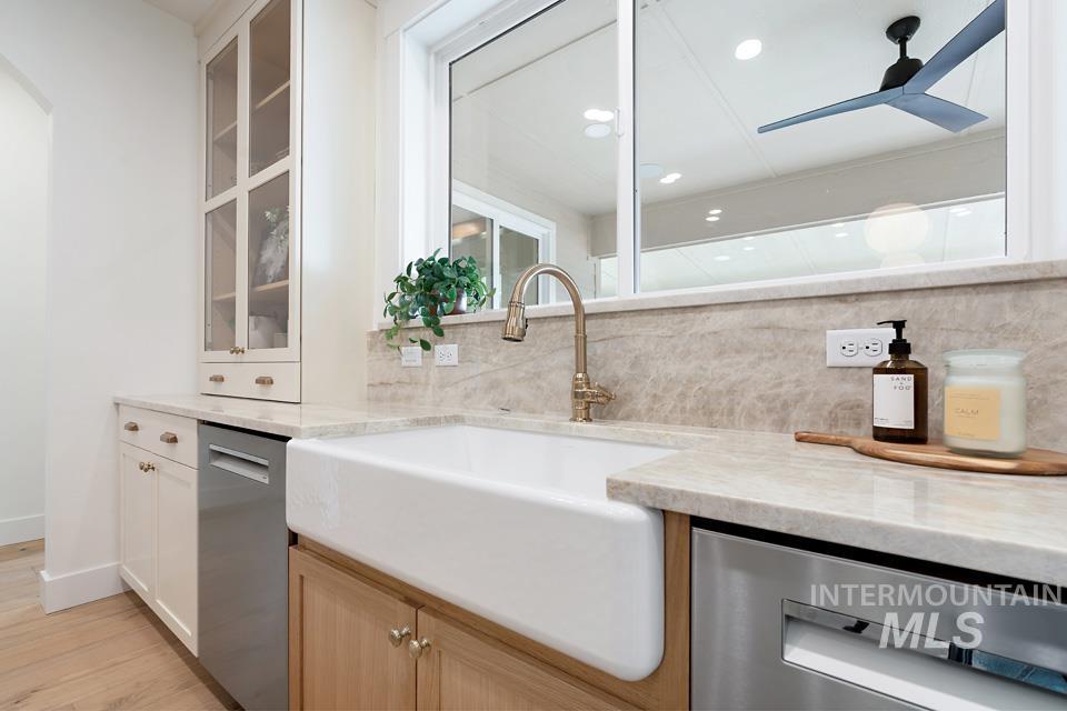 Kitchen with tasteful backsplash, stainless steel dishwasher, light stone countertops, white cabinets, and recessed lighting