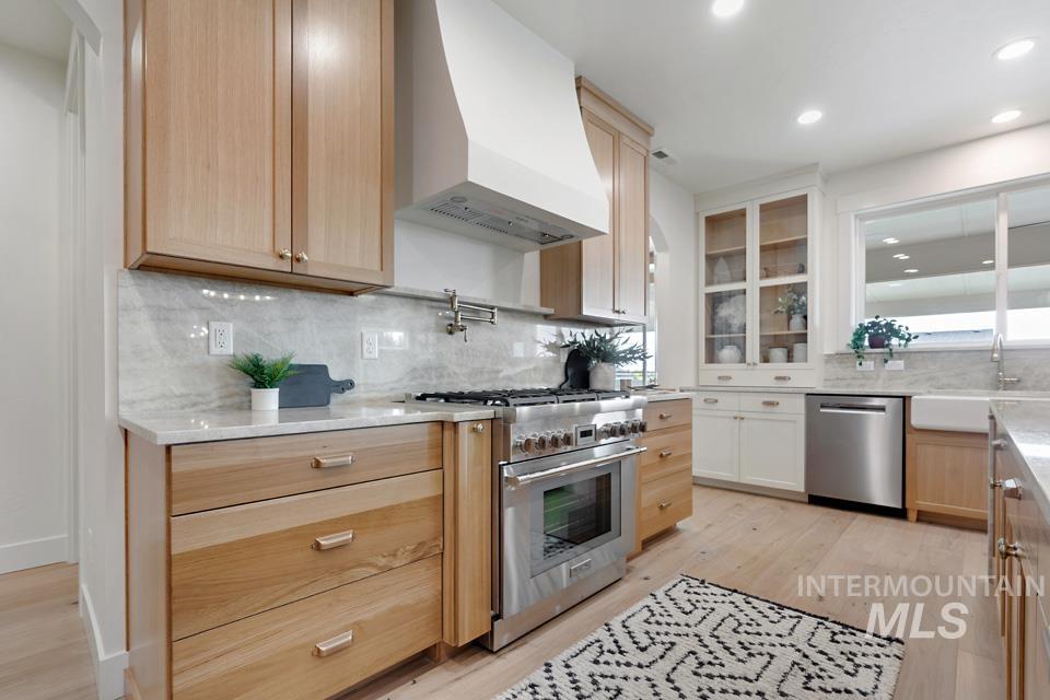 Kitchen featuring premium range hood, light brown cabinetry, stainless steel appliances, tasteful backsplash, and recessed lighting