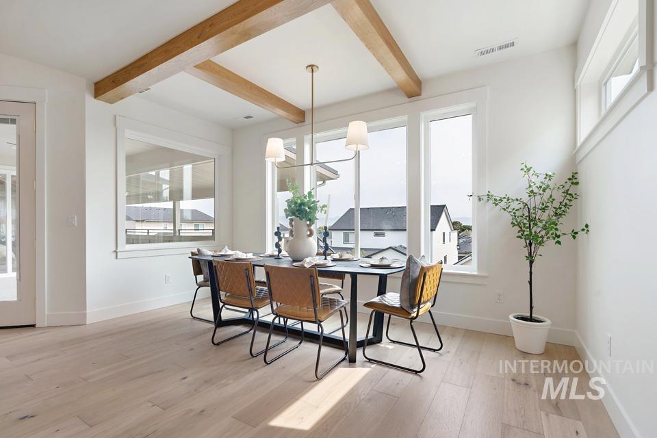 Dining room with beam ceiling, light wood-style floors, and a chandelier