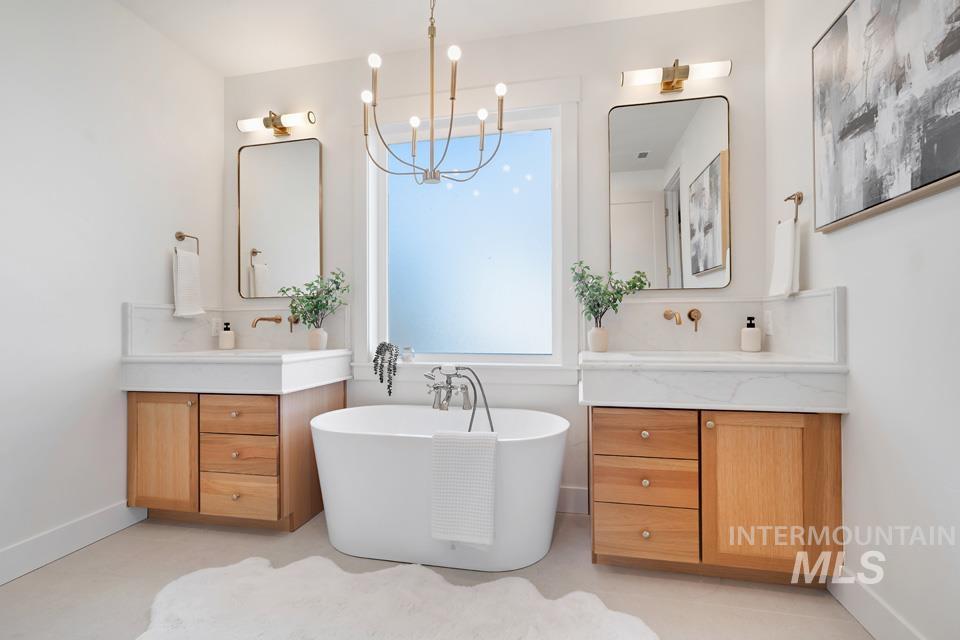 Bathroom with two vanities, a freestanding bath, and a chandelier