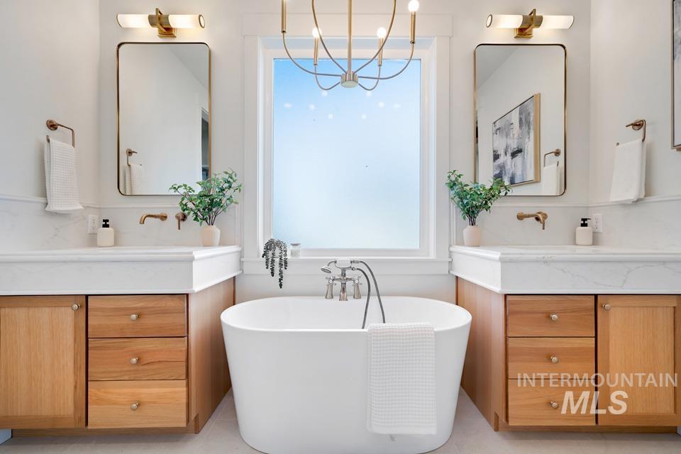 Bathroom with two vanities, a freestanding bath, and a chandelier