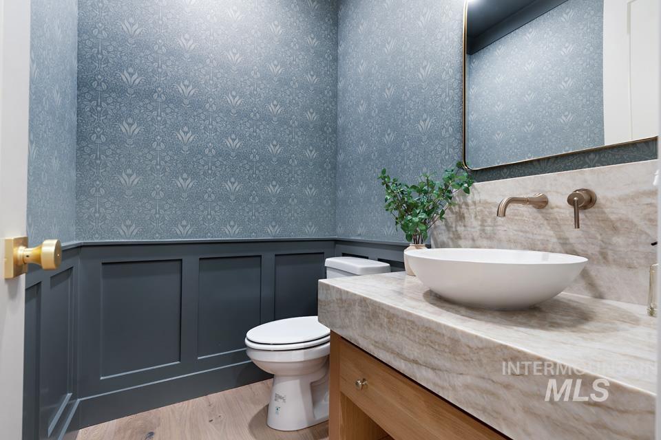 Bathroom featuring a wainscoted wall, vanity, a decorative wall, light wood-type flooring, and wallpapered walls