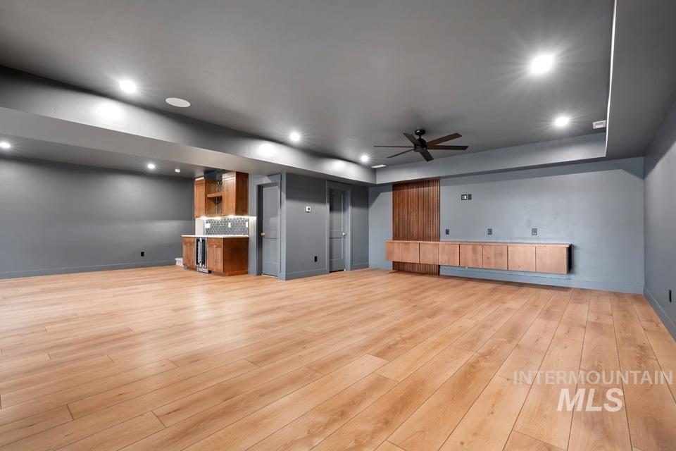 Unfurnished living room featuring wet bar, light wood finished floors, ceiling fan, and recessed lighting