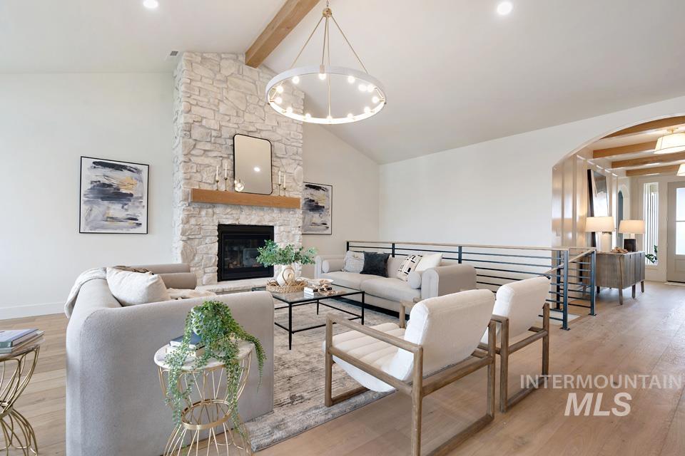 Living area with light wood-style flooring, a fireplace, arched walkways, and a chandelier